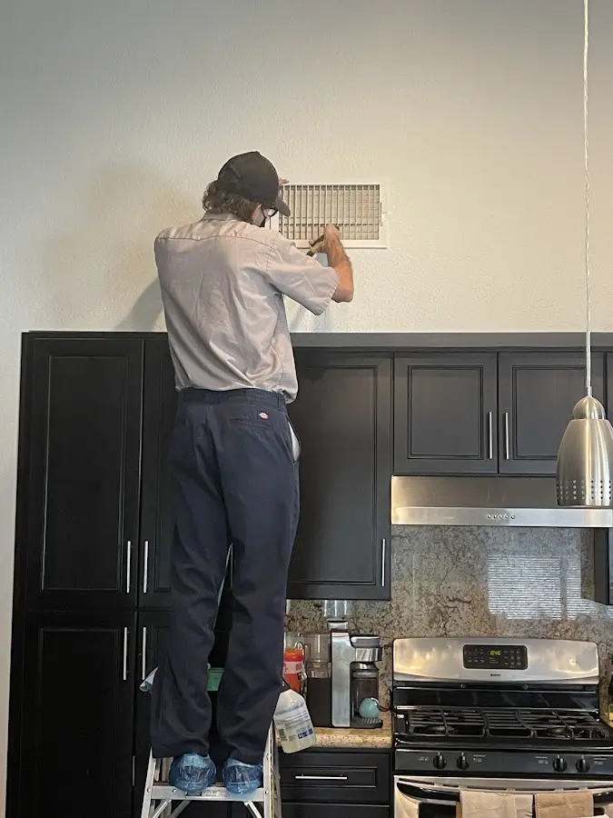 Technician inspecting an air vent during HVAC service in Midland Park